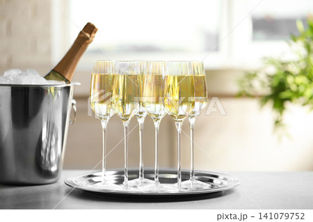 Glasses of champagne and ice bucket with bottle on grey table Glasses of champagne and ice bucket with bottle on grey table 141079752