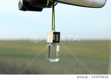 Air freshener hanging on rear view mirror in car 141079816