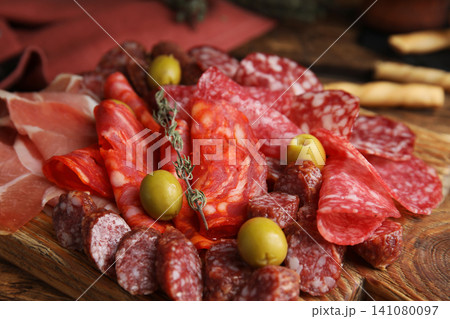 Tasty prosciutto with other delicacies served on wooden table, closeup Tasty prosciutto with other delicacies served on wooden table, closeup 141080097