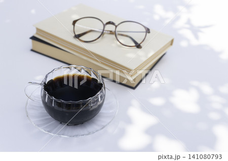 木漏れ日のコーヒーブレイク 積み重ねた本と眼鏡のあるライフスタイル 木漏れ日のコーヒーブレイク 積み重ねた本と眼鏡のあるライフスタイル 141080793