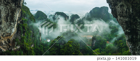 Breathtaking View from a Cave Overlooking Misty Limestone Mountains for Eco-Tourism Breathtaking View from a Cave Overlooking Misty Limestone Mountains for Eco-Tourism 141081019