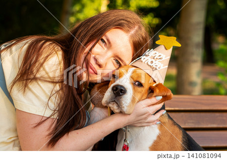 Young Woman Hugging Beagle Wearing Birthday Hat Young Woman Hugging Beagle Wearing Birthday Hat 141081094