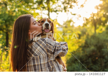 Woman Kissing Happy Beagle During Outdoor Walk Woman Kissing Happy Beagle During Outdoor Walk 141081127
