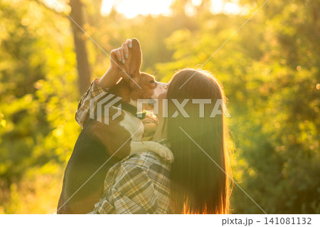 Woman Kissing Beagle During Golden Hour in Forest 141081132