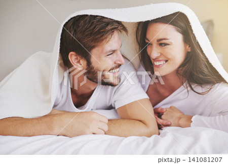 Happy, love and couple in conversation with blanket for relaxing, bonding and resting on bed together. Happy, romantic and young man and woman laying with duvet in bedroom at hotel, home or apartment Happy, love and couple in conversation with blanket for relaxing, bonding and resting on bed together. Happy, romantic and young man and woman laying with duvet in bedroom at hotel, home or apartment 141081207