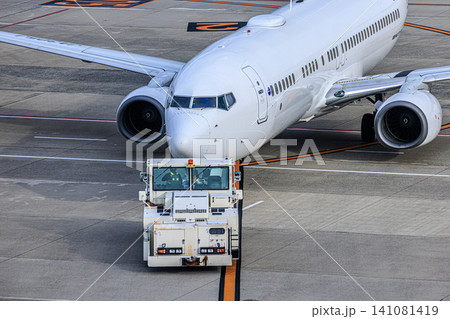 空港の駐機場でトーイングカーに牽引される旅客機 空港の駐機場でトーイングカーに牽引される旅客機 141081419