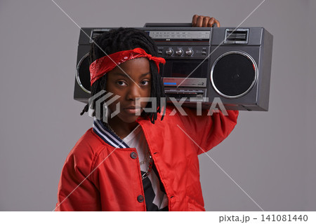 Child, hip hop and portrait with radio for cool music and dance in a studio with urban clothing. Fashion, African kid and boombox with trendy clothes and rap swag with confidence and grey background Child, hip hop and portrait with radio for cool music and dance in a studio with urban clothing. Fashion, African kid and boombox with trendy clothes and rap swag with confidence and grey background 141081440