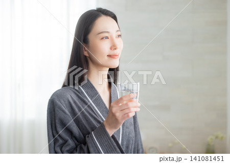 窓辺で水を飲む若い女性 窓辺で水を飲む若い女性 141081451