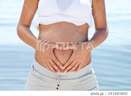 Pregnant woman, mom and heart hands on belly at beach, love and family with wellness, self care and ocean fresh air. Health, pregnancy and motherhood with maternity, prenatal and baby bump outdoor Pregnant woman, mom and heart hands on belly at beach, love and family with wellness, self care and ocean fresh air. Health, pregnancy and motherhood with maternity, prenatal and baby bump outdoor 141081602