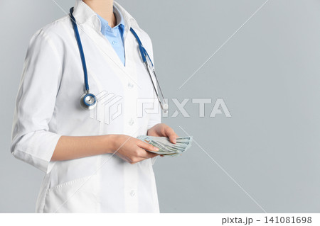 Doctor with bribe on grey background, closeup. Corruption in medicine Doctor with bribe on grey background, closeup. Corruption in medicine 141081698