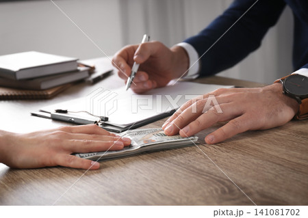 Woman giving bribe to man at table in office, closeup 141081702