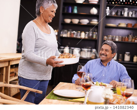 Senior, happy woman and family with turkey for thanksgiving dinner, meal or food at the table. Mature and hungry couple with smile for dining, eating or lunch in happiness together at the house 141082340