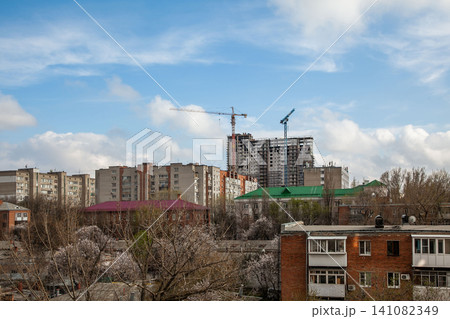 Urban skyline with construction cranes and residential buildings under blue sky Urban skyline with construction cranes and residential buildings under blue sky 141082349