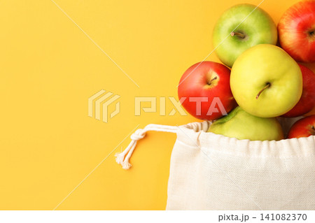 Cotton eco bag and apples on yellow background, flat lay. Space for text 141082370