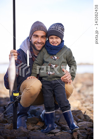 Portrait, kid and smile with dad, fish and happiness for achievement on break. Child, water and ocean with rocks, adventure and vacation on fishing trip with childhood memories and fun success 141082438