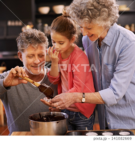 Teaching, baking and grandparents with girl, smile and ingredients with help and bonding together. Family, senior man or old woman with grandchild, happy or utensils with recipe or hobby in a kitchen 141082669