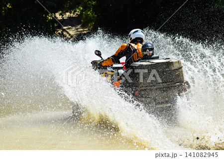 The man on the ATV crosses a stream. Tourist walks on a cross-country terrain 141082945
