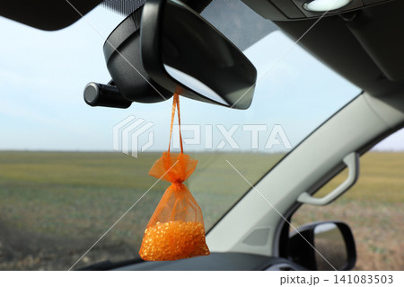 Air freshener hanging on rear view mirror in car Air freshener hanging on rear view mirror in car 141083503