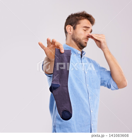 Man, smelly socks and close nose for poor hygiene with clothes, bad odor or stink with disgust isolated on white background. Unpleasant, dirty and foul with negative reaction for stench in studio 141083608