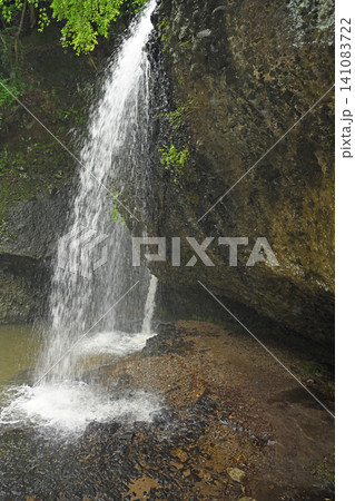 岩壁を穿つ激しい水 月待の滝の裏側に広がる神秘的な空間と流れ落ちる清涼な大自然風景 岩壁を穿つ激しい水 月待の滝の裏側に広がる神秘的な空間と流れ落ちる清涼な大自然風景 141083722