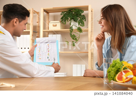Nutritionist consulting patient at table in clinic Nutritionist consulting patient at table in clinic 141084040