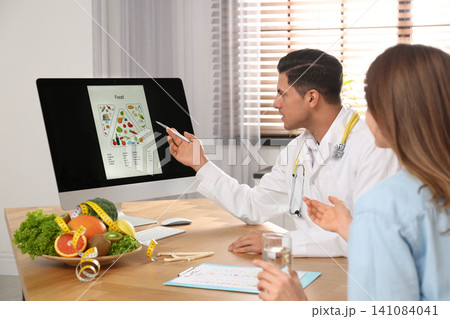 Nutritionist consulting patient at table in clinic Nutritionist consulting patient at table in clinic 141084041