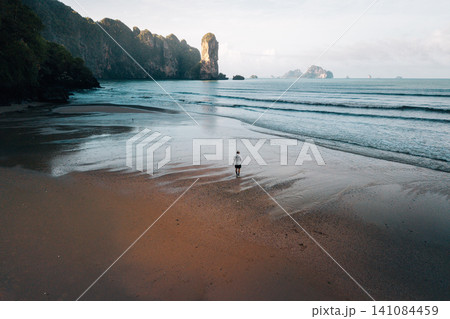 Lonely traveler walking on a pristine tropical beach at low tide with limestone islands, Krabi. Lonely traveler walking on a pristine tropical beach at low tide with limestone islands, Krabi. 141084459