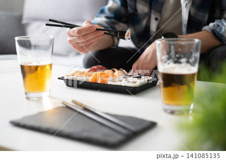 Man eating sushi with chopsticks Man eating sushi with chopsticks 141085135