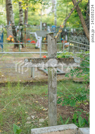 serene wooden cross standing upright in a cemetery with a metal fence and flowers, ground-level perspective, green and brown tones, religious imagery, memorial photography, cemetery scenes. serene wooden cross standing upright in a cemetery with a metal fence and flowers, ground-level perspective, green and brown tones, religious imagery, memorial photography, cemetery scenes. 141085234