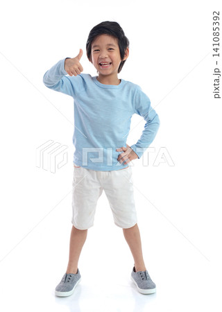 A cheerful young boy smiling and giving a thumbs up, showing a positive gesture, isolated on a white background. A cheerful young boy smiling and giving a thumbs up, showing a positive gesture, isolated on a white background. 141085392