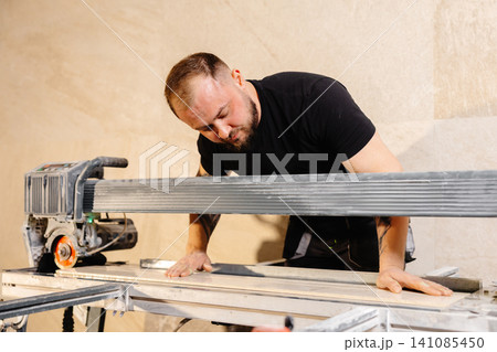 Construction worker using tile saw cutting machine preparing ceramic tiles for bathroom renovation Construction worker using tile saw cutting machine preparing ceramic tiles for bathroom renovation 141085450
