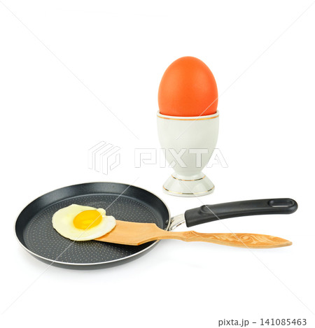 Fried Egg in a Frying Pan and Raw Brown Egg in Cup Isolated on White Healthy Breakfast Cooking Concept with Fried and Whole Eggs Fried Egg in a Frying Pan and Raw Brown Egg in Cup Isolated on White Healthy Breakfast Cooking Concept with Fried and Whole Eggs 141085463