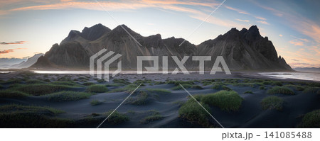 Panoramic view of the iconic Vestrahorn mountain rising above black volcanic sand dunes and grassy mounds at sunset. One of Iceland's most breathtaking coastal landscapes. Panoramic view of the iconic Vestrahorn mountain rising above black volcanic sand dunes and grassy mounds at sunset. One of Iceland's most breathtaking coastal landscapes. 141085488