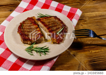 Grilled pork steaks with rosemary on wooden table Grilled pork steaks with rosemary on wooden table 141085660