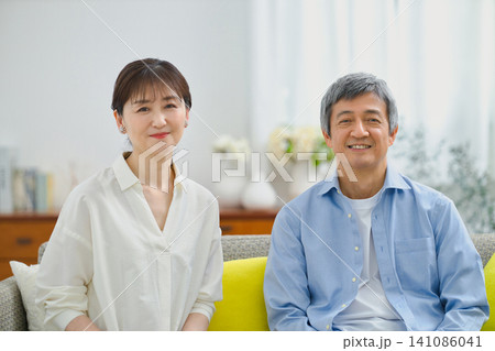 ソファーに座ってリラックスする笑顔のシニアの夫婦 ソファーに座ってリラックスする笑顔のシニアの夫婦 141086041