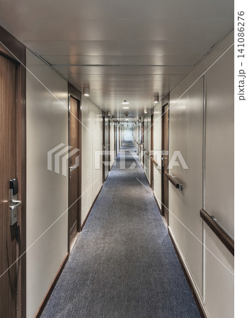 Long narrow corridor inside a cruise ship or hotel with wooden doors. Long narrow corridor inside a cruise ship or hotel with wooden doors. 141086276