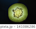 Backlit kiwi fruit slice glowing against a dark background. 141086286