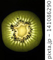 Glowing kiwi slice close-up on black background. 141086290
