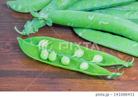 Fresh, ripe peas on a wooden background; healthy organic vegetables, close-up. Fresh, ripe peas on a wooden background; healthy organic vegetables, close-up. 141086431