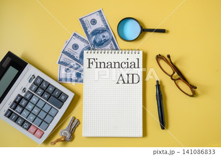 Text FINANCIAL AID write on booknote and pen ,banknote and calculator. Text FINANCIAL AID write on booknote and pen ,banknote and calculator. 141086833