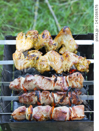 Grilling juicy shashlik and chicken skewers on an outdoor mangal for a perfect barbecue Grilling juicy shashlik and chicken skewers on an outdoor mangal for a perfect barbecue 141086976
