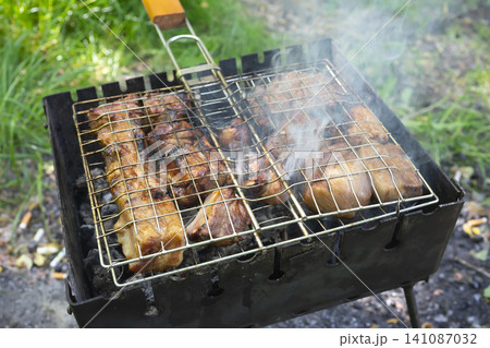 Weekend shashlik grill with sizzling meat over fire in outdoor setting Weekend shashlik grill with sizzling meat over fire in outdoor setting 141087032