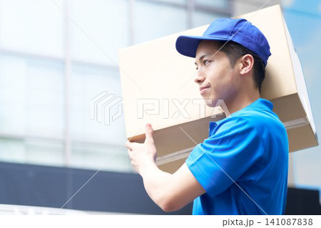 荷物を肩に担いで運ぶ配送スタッフの横顔 荷物を肩に担いで運ぶ配送スタッフの横顔 141087838