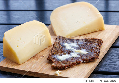 Sourdough wholegrain rye bread with melting butter, served with cheese on a wooden board. Sourdough wholegrain rye bread with melting butter, served with cheese on a wooden board. 141087860