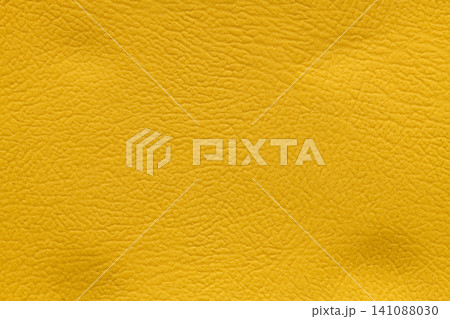 Full-frame macro shot detailing the distinctive, finely textured surface of a bright and vivid mustard yellow leather material Full-frame macro shot detailing the distinctive, finely textured surface of a bright and vivid mustard yellow leather material 141088030