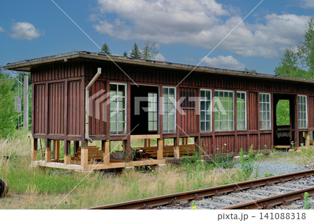 Old abandoned wooden railway station building next to empty train tracks Old abandoned wooden railway station building next to empty train tracks 141088318