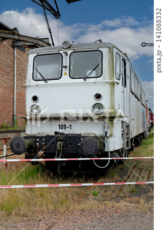 Old White Electric Locomotive Front View Behind Warning Tape at a Railway Depot Old White Electric Locomotive Front View Behind Warning Tape at a Railway Depot 141088332