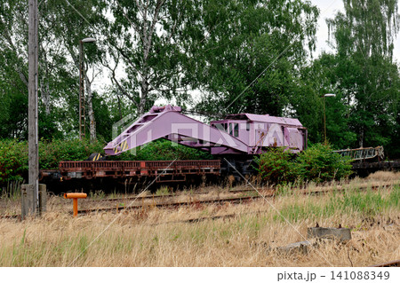 Heavy purple industrial railway crane car on tracks among dry grass Heavy purple industrial railway crane car on tracks among dry grass 141088349