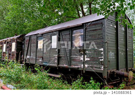 Weathered old green wooden train car abandoned on tracks in a forest Weathered old green wooden train car abandoned on tracks in a forest 141088361