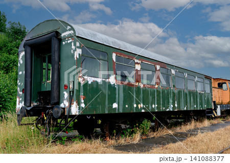 Old abandoned green passenger train wagon with peeling paint on overgrown tracks Old abandoned green passenger train wagon with peeling paint on overgrown tracks 141088377